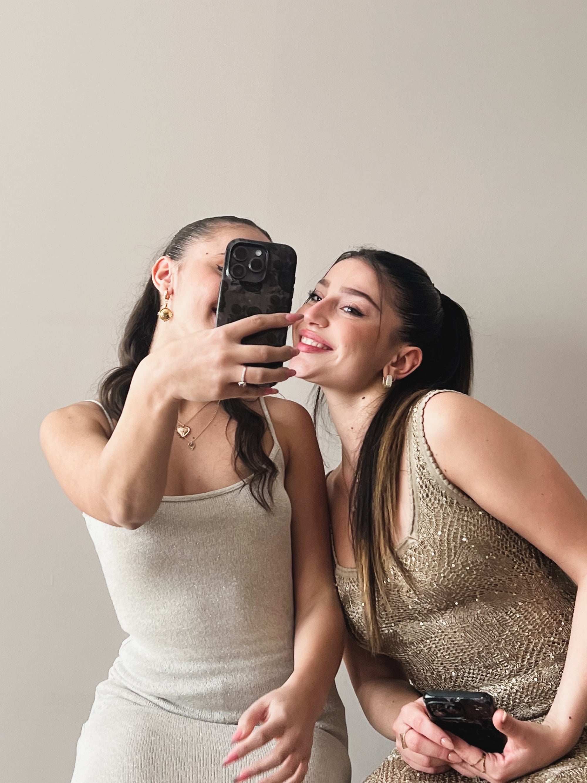 image showing two girls taking a selfie holding a phone with our designed phone case in fancy dresses with natural beige background .